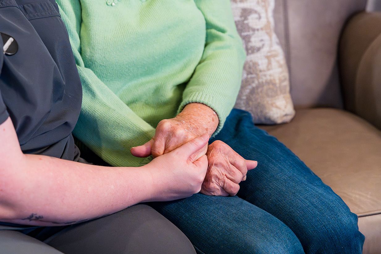 Close up of a staff member holding a residents hand