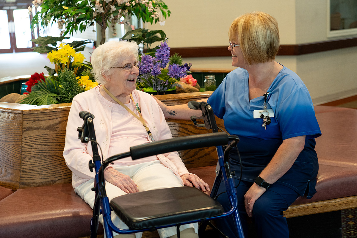 An older woman happily talking with a member of the nursing staff